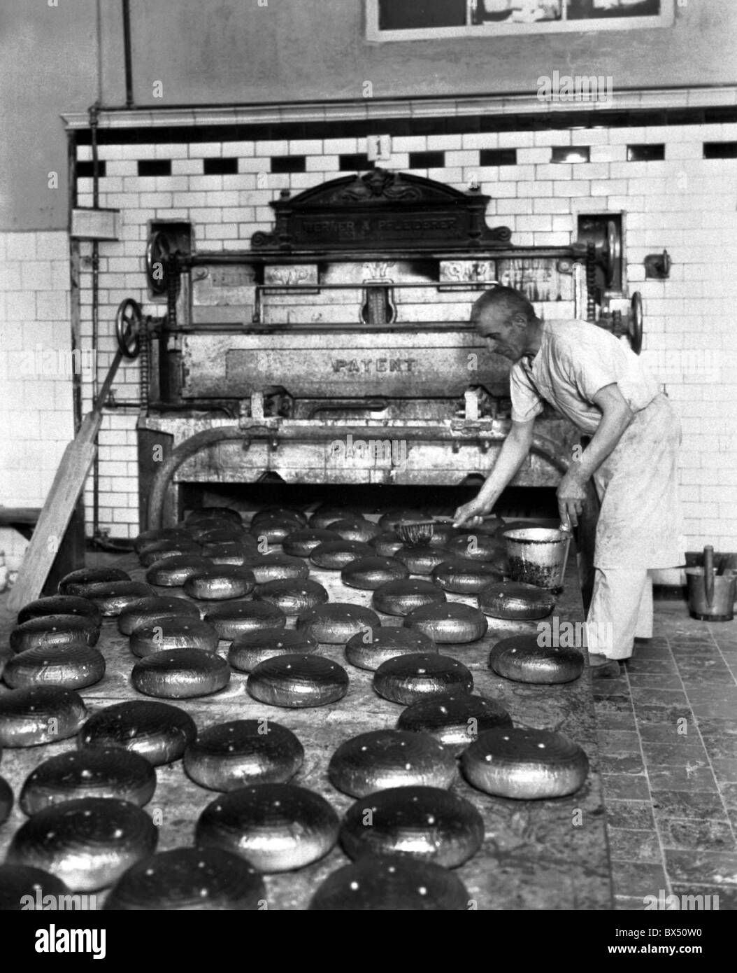 Czechoslovakia 1937, vintage photograph of bakery. Bread loafs being buttered. Stock Photo