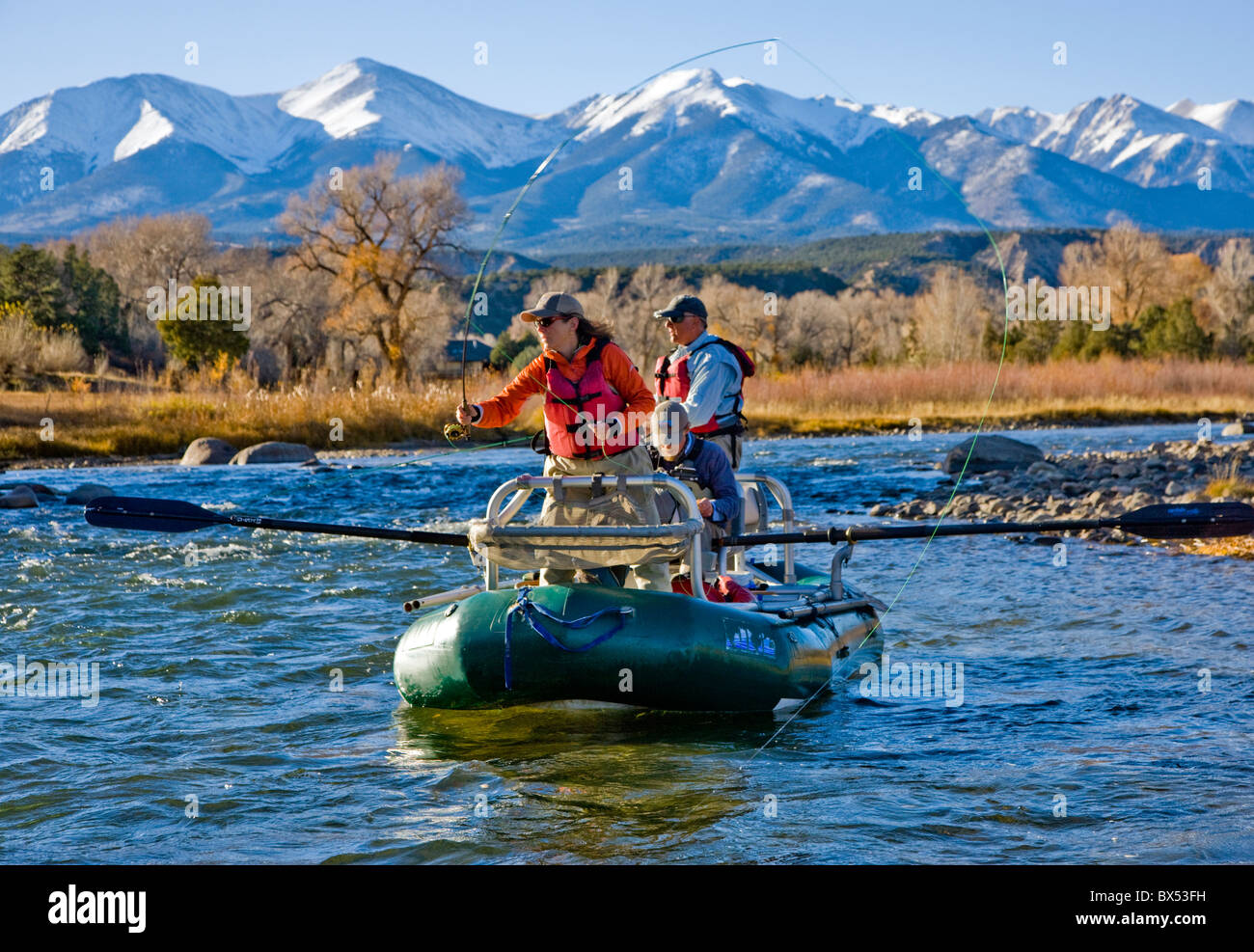 Married couple and professional guide fly fishing from a boat on the