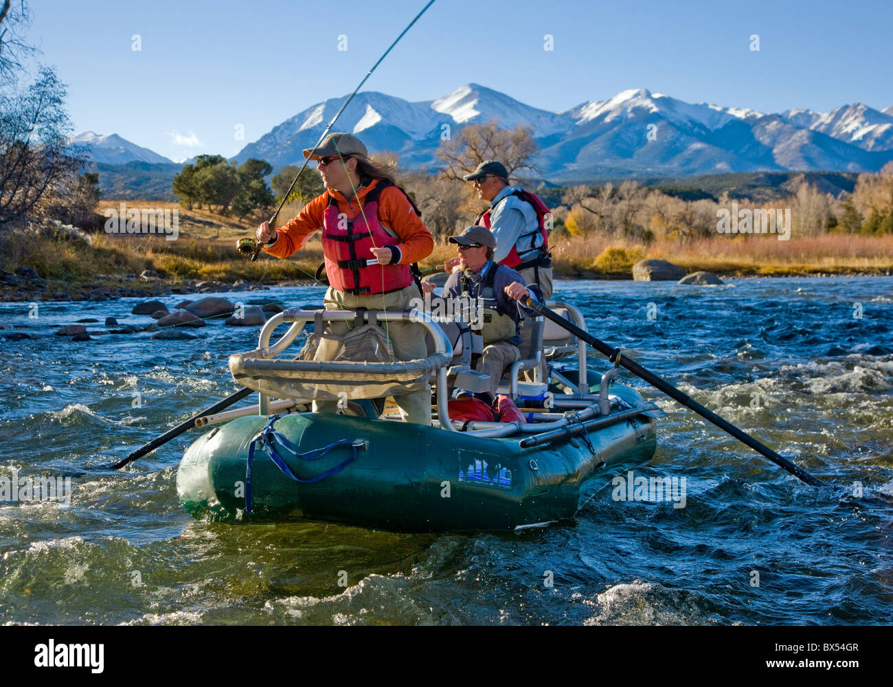 Married couple and professional guide fly fishing from a boat on the