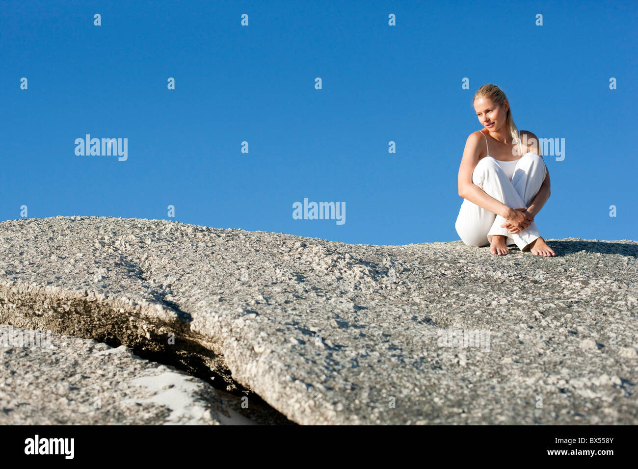 Woman sitting on rock hi-res stock photography and images - Alamy