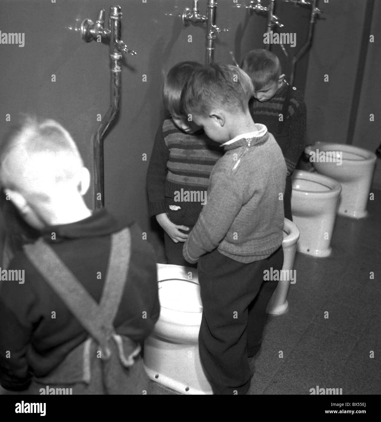 little boy standing in pull-ups in the bathroom looking miserable