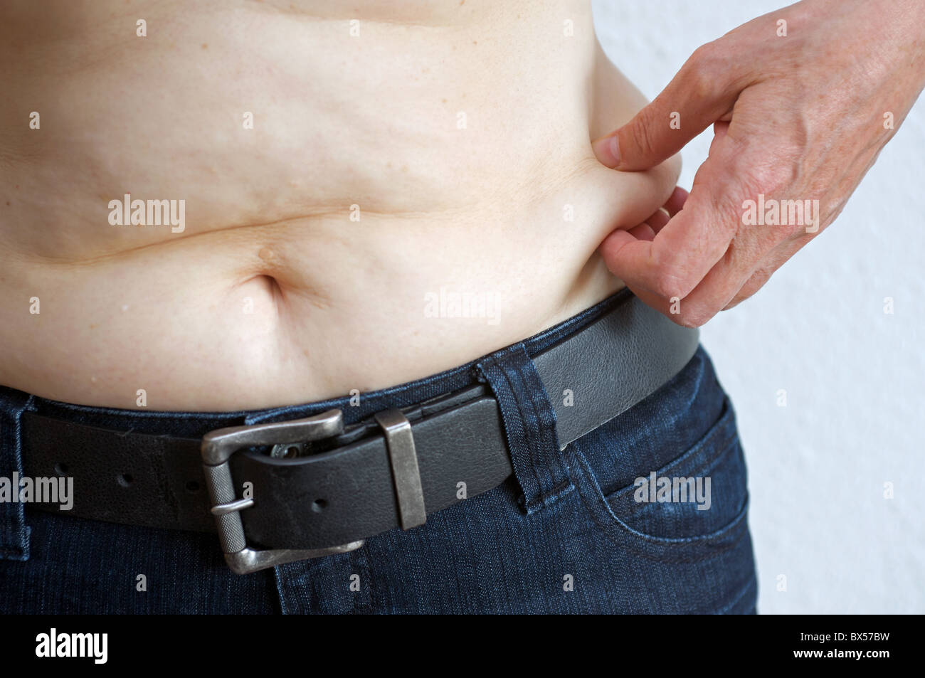 Middle aged woman pinching fat around her tummy Stock Photo