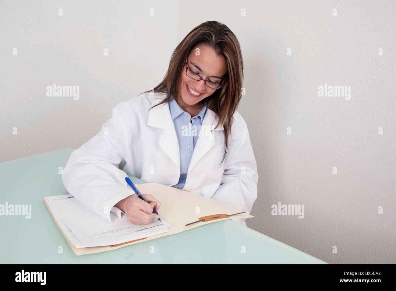 Smiling young doctor working on a patient file Stock Photo