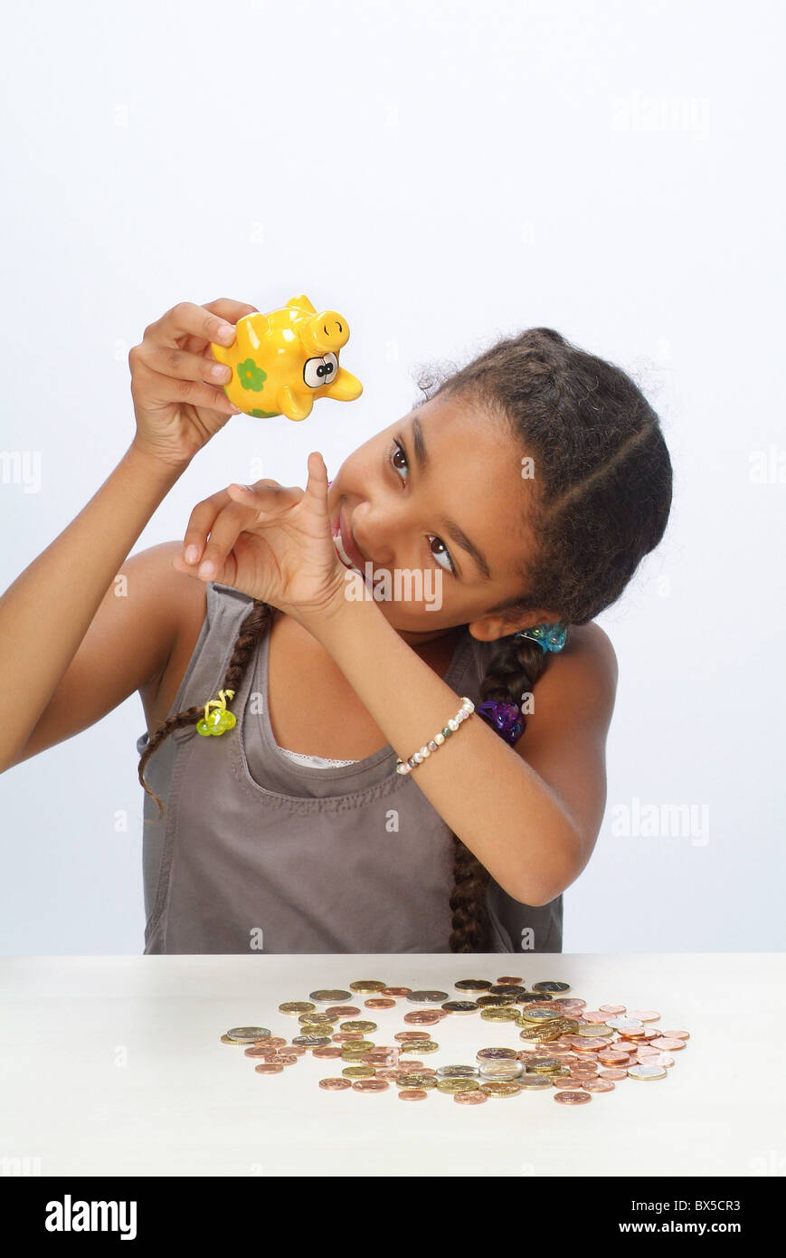 A girl with her savings and a piggy bank Stock Photo - Alamy