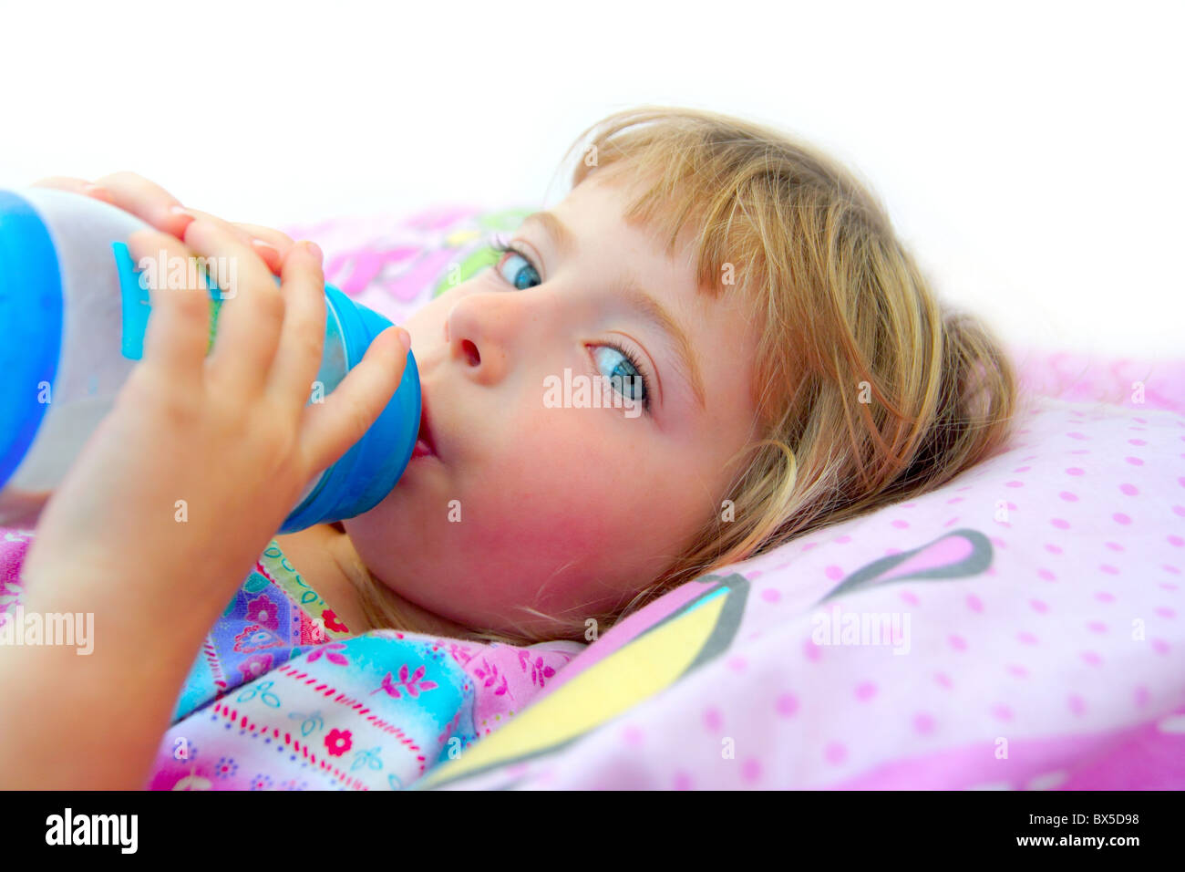 girl drinking bottle of milk laying on bed blond toddler Stock Photo Alamy