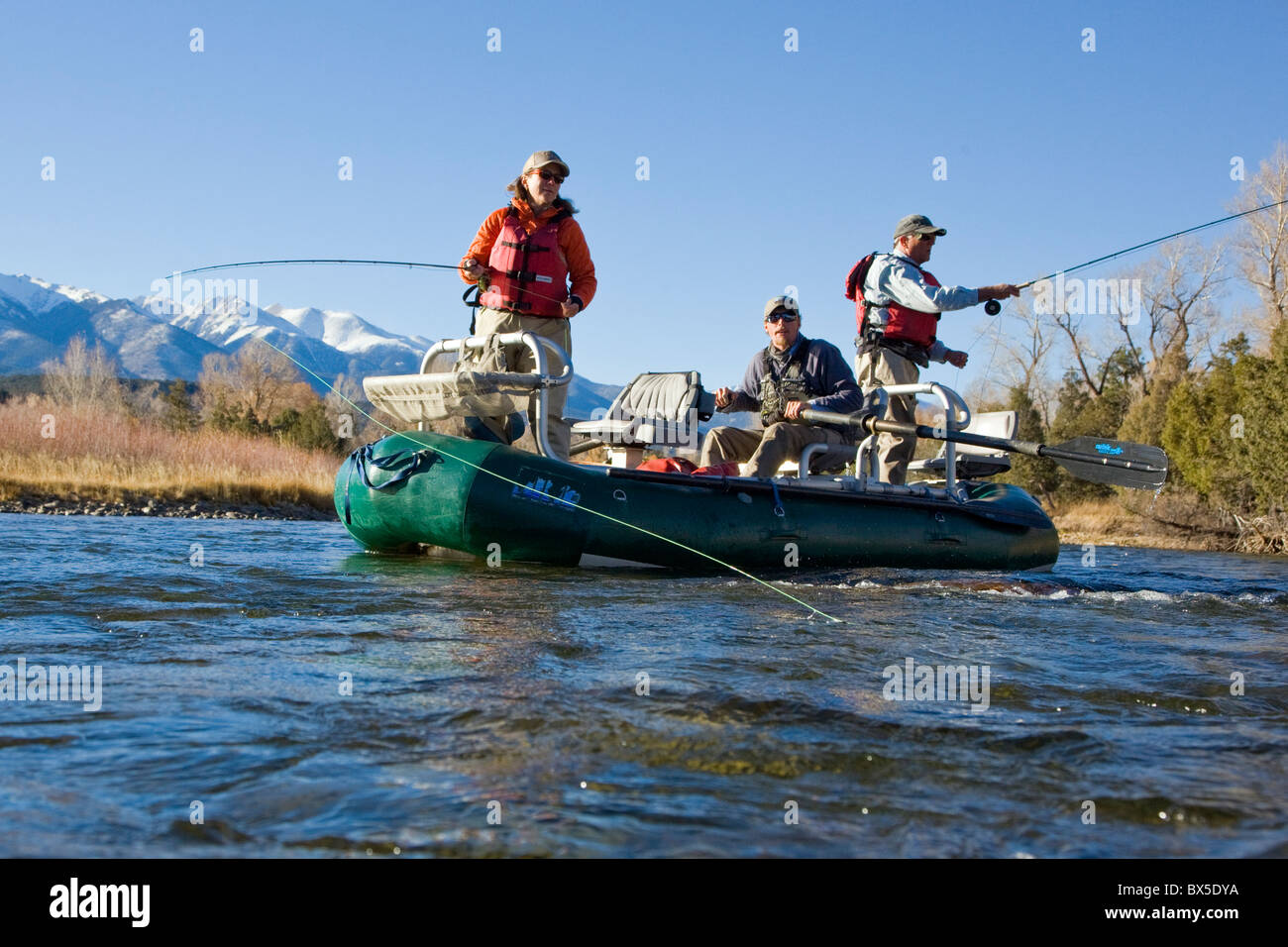 Married couple and professional guide fly fishing from a boat on the