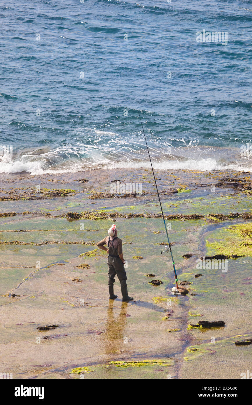 Man fishing on rocky shore Stock Photo