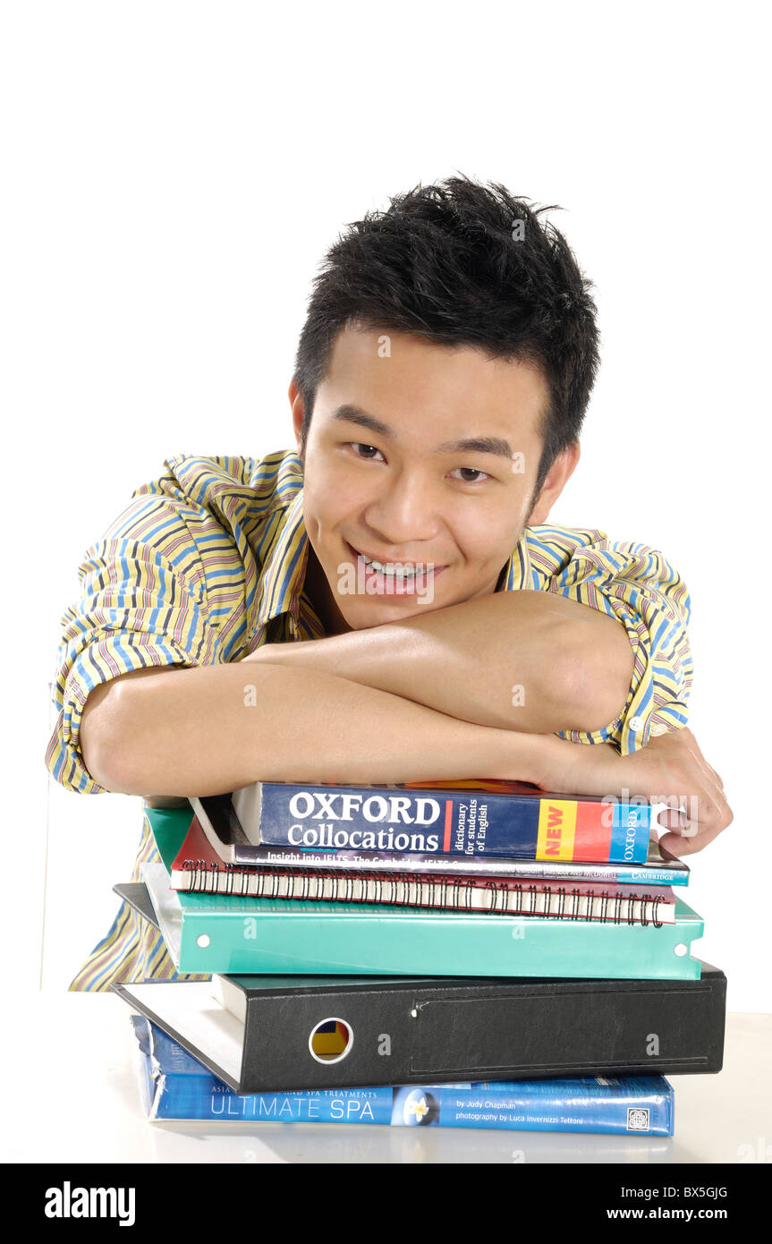 Male university student leaning on stack of books Stock Photo - Alamy