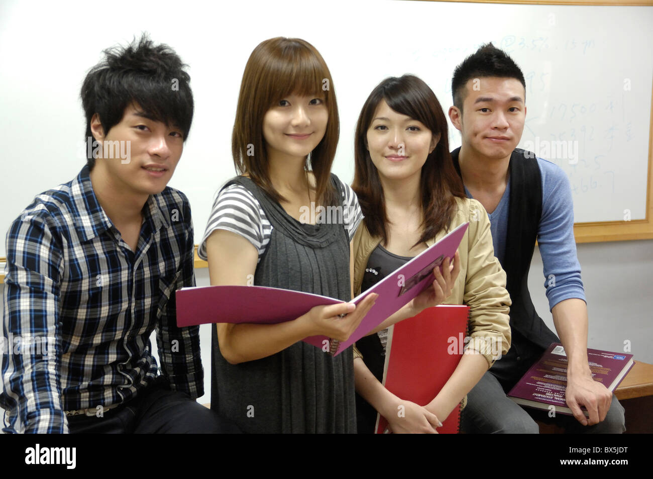University students holding books and smiling in a classroom Stock ...