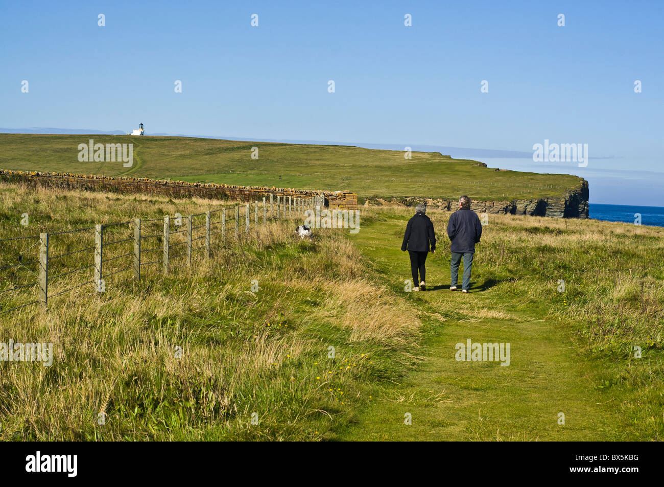 dh  BIRSAY ORKNEY Two walkers on footpath with dog Brough of Birsay north coastal path Stock Photo