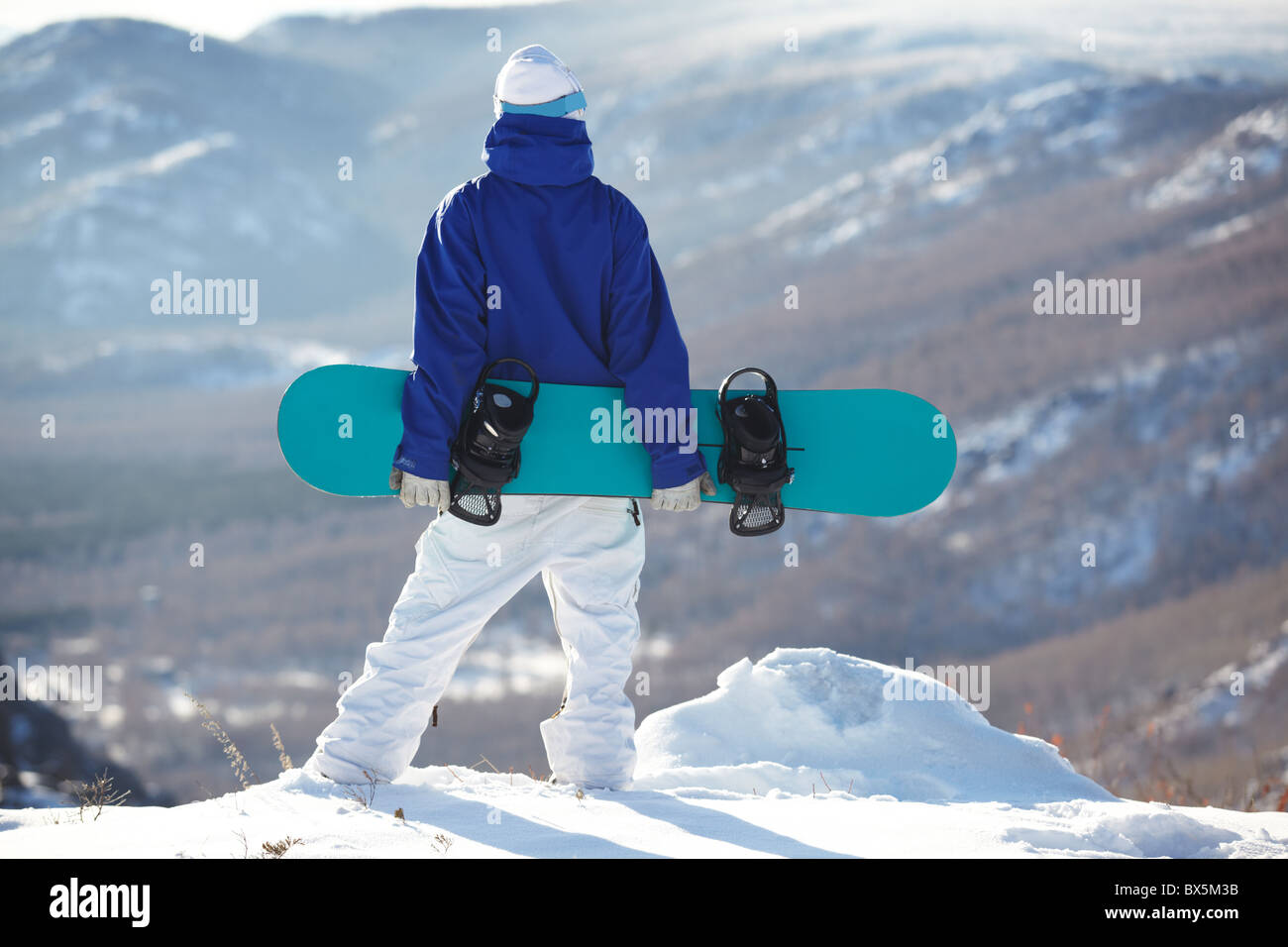 Rear view of sportsman with snowboard standing on top of mount Stock ...