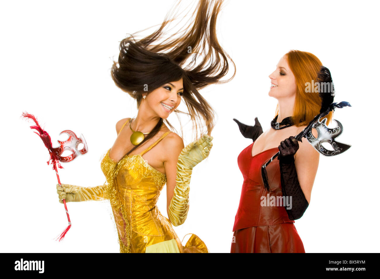 Photo of joyful actresses in fashionable dresses having fun over white background Stock Photo