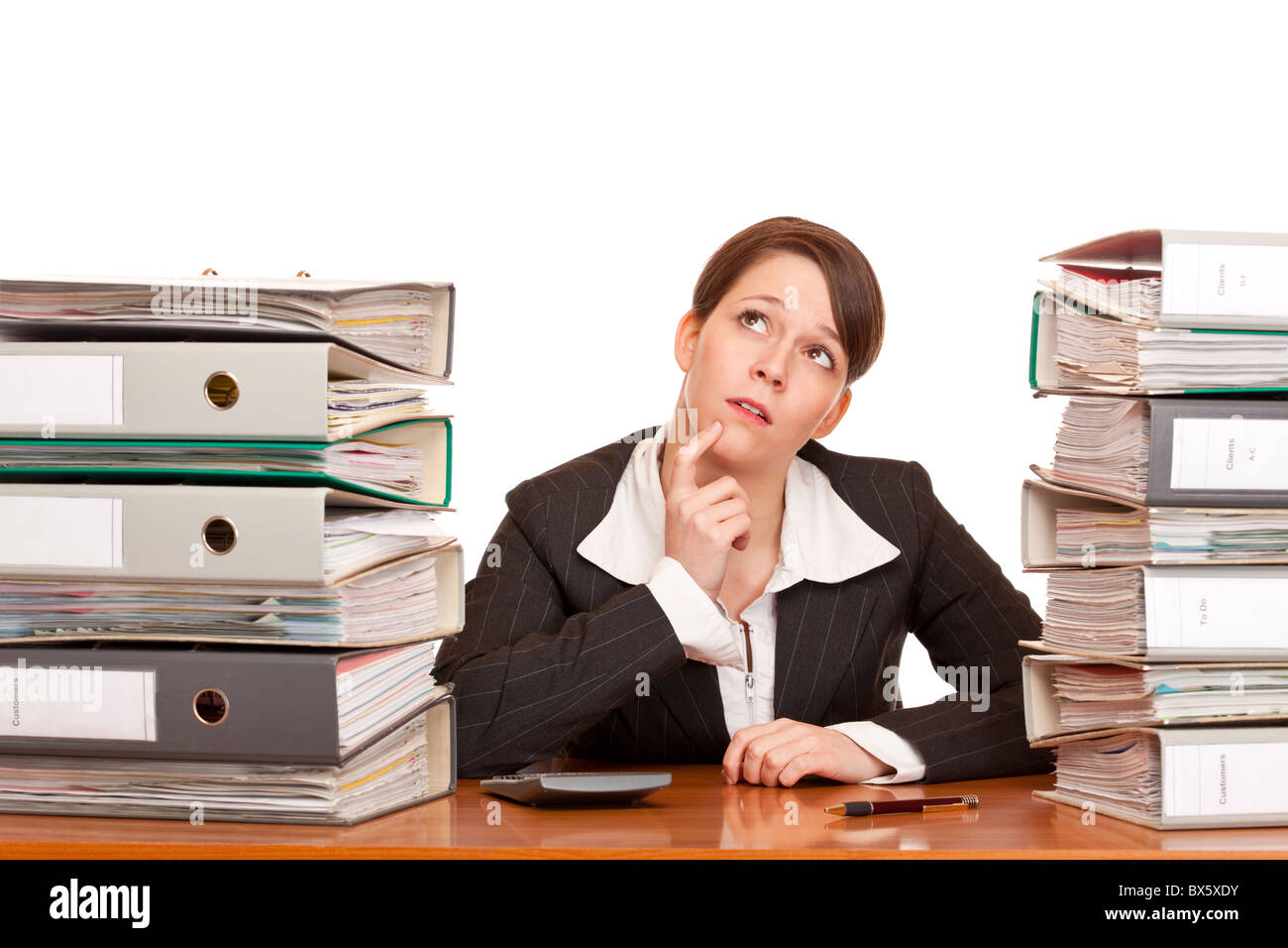 overworked contemplative business woman in office between folder stacks. Isolated on white background. Stock Photo