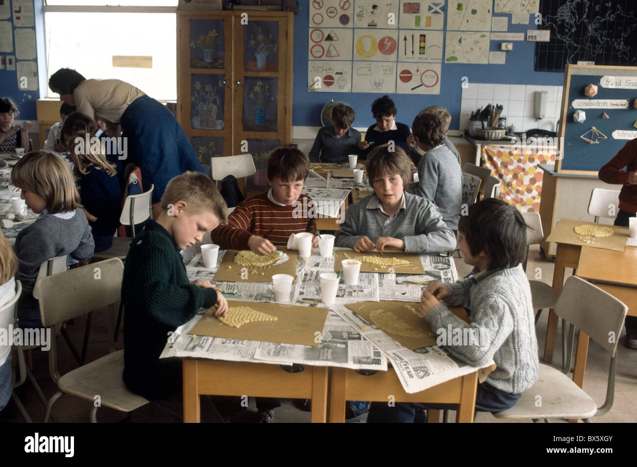 archive historical image of primary school classroom with 7 year old children creating  pictures with macaroni and glue Stock Photo