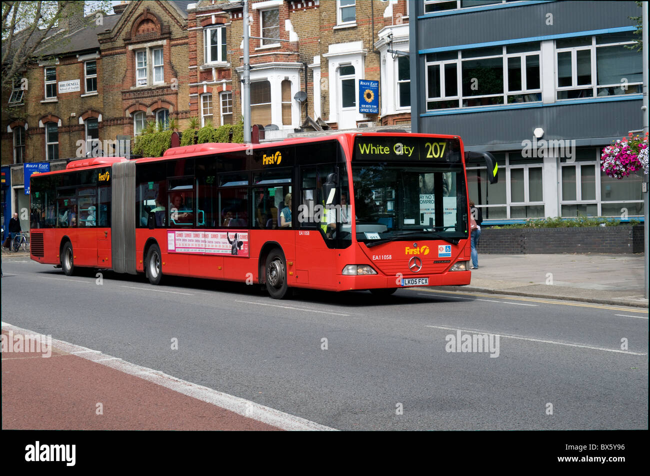 An articulated (bendy) bus passes through Ealing on its way to White City in West London. It is operated by First bus group Stock Photo