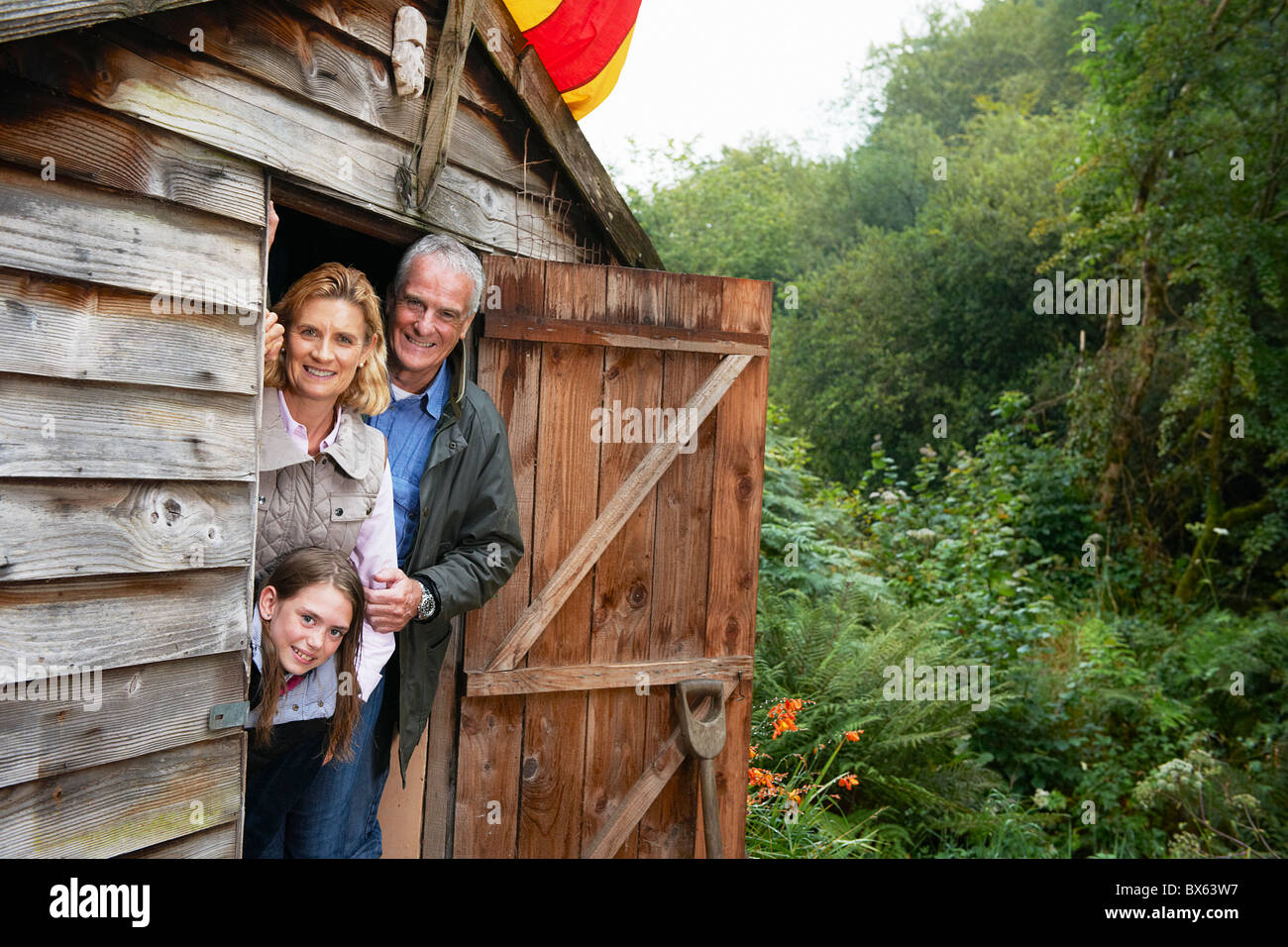 Grandparents and girl hiding in shed Stock Photo
