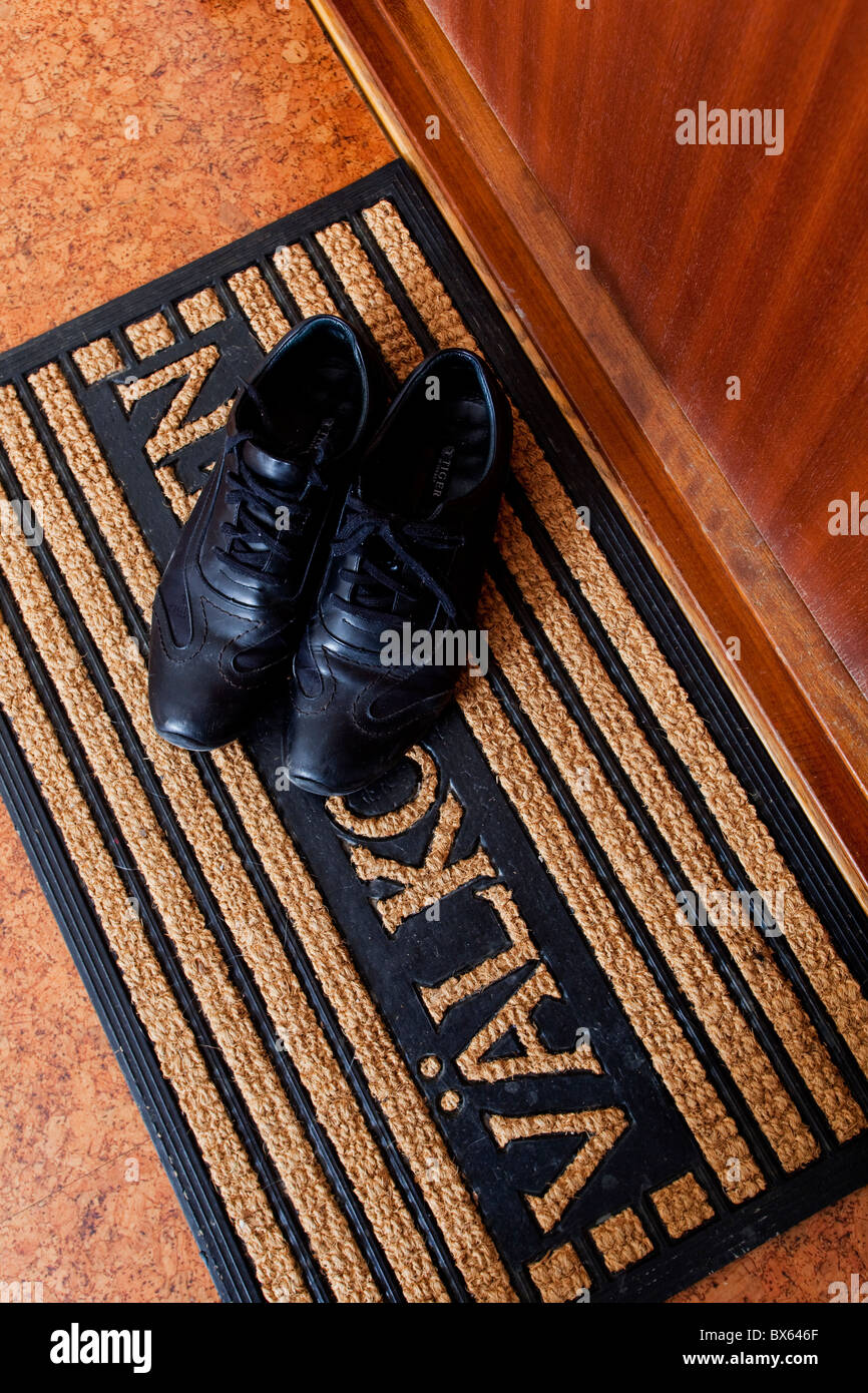 Doormat with the text'Welcome' and a pair of shoes. Stock Photo