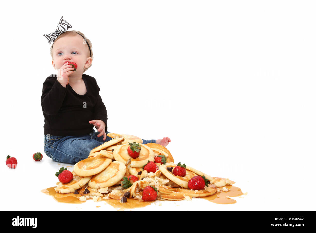 Adorable 10 month old baby girl sitting in stack of pancakes with