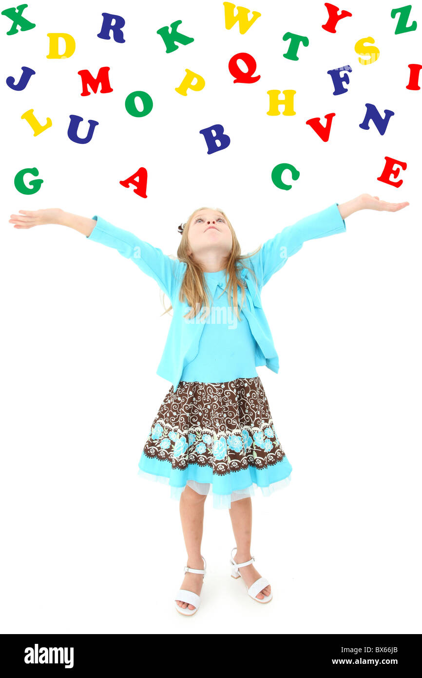 Adorable six year old girl tossing colorful alphabet into the air over white background. Stock Photo