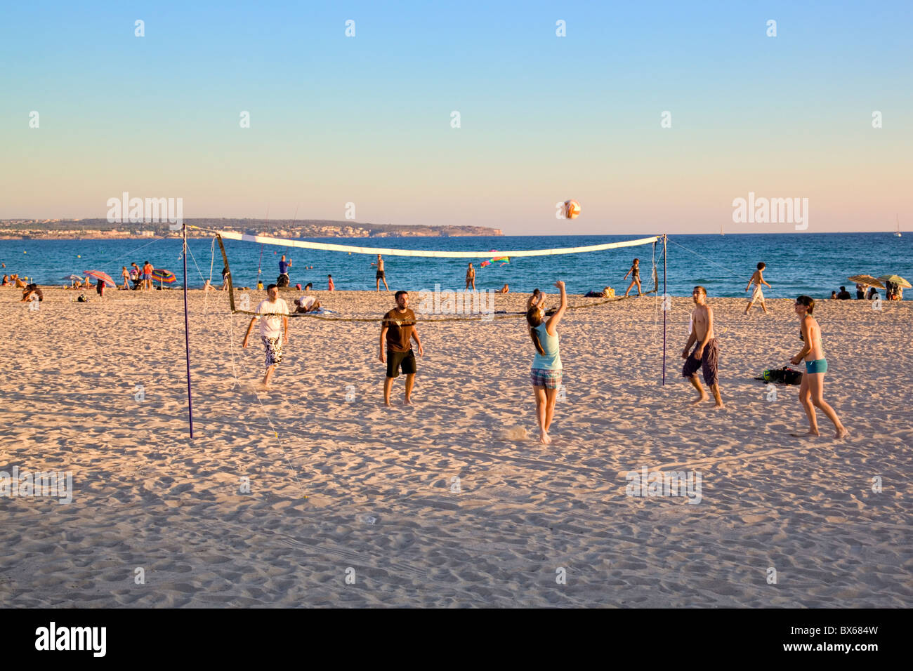 Five young boys and girls playing volleyball on the beach at dusk Stock Photo