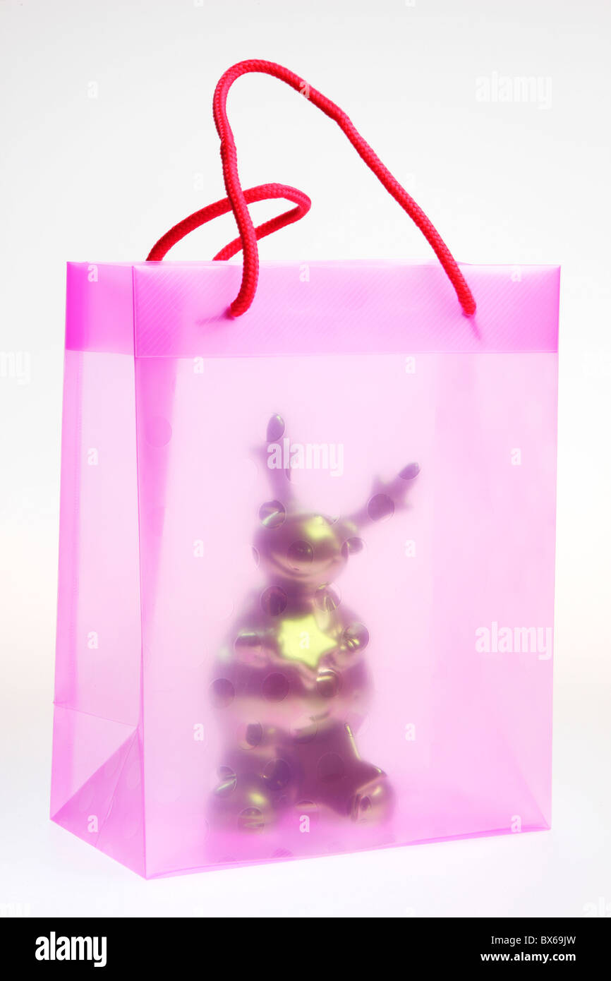 Pink, transparent, plastic, gift bag, with a Christmas toy figure. Stock Photo