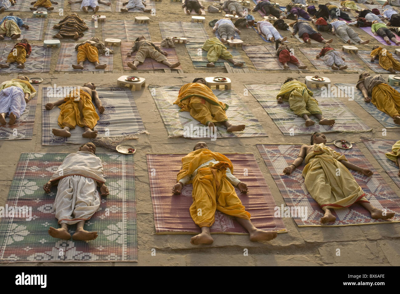 Students of Sanskrit school performing the savasana posture during daily yoga at sunrise, ghat of Varanasi, Uttar Pradesh, India Stock Photo