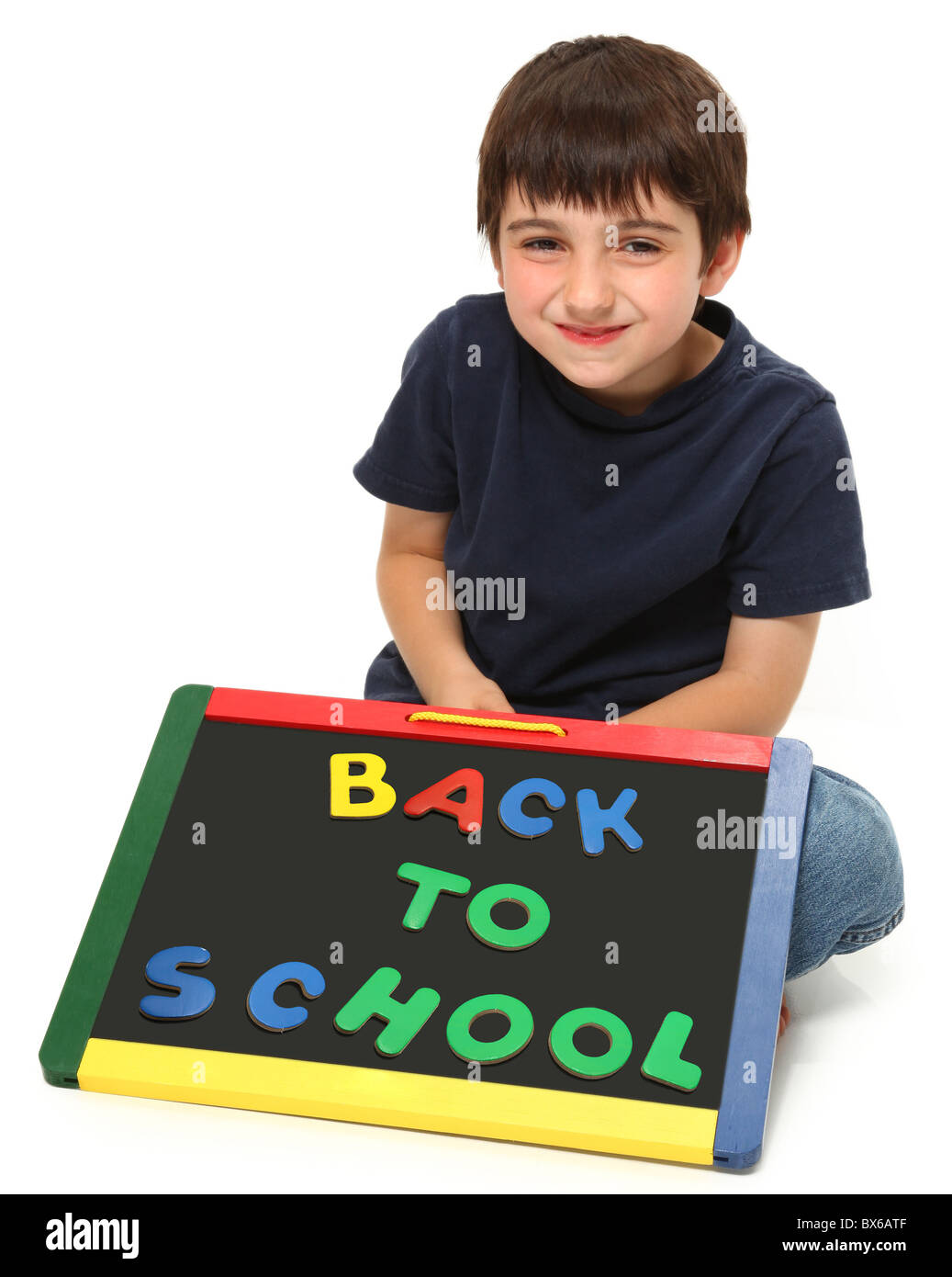 adorable seven year old boy holding back to school chalk board Stock Photo