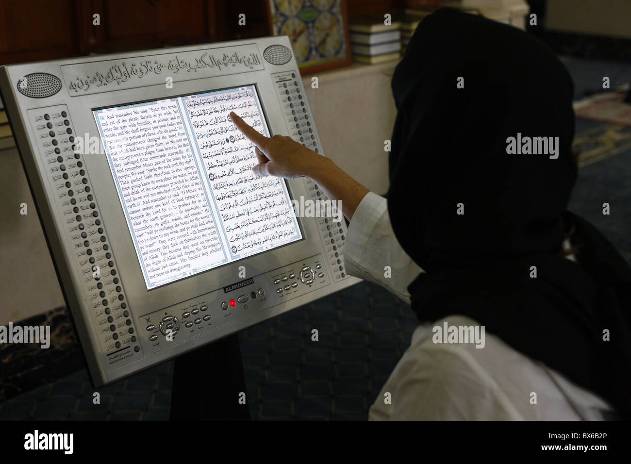 Woman reading an Arabic and English electronic version of The Holy Koran, Dubai, United Arab Emirates, Middle East Stock Photo