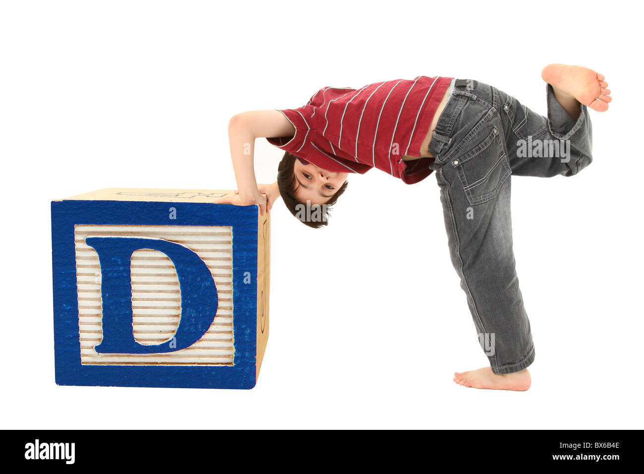 Adorable seven year old boy pushing a wooden block letter D. Stock Photo