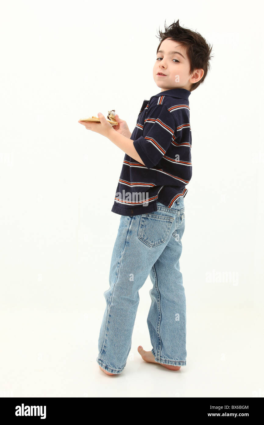 Adorable six year old boy laughing and eating pop tarts. Sitting on white floor. Stock Photo