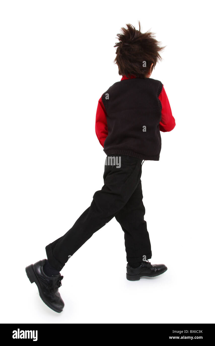 Adorable 7 year old boy in sweater vest suit over white background walking fast. Motion blur on head and feet. Stock Photo