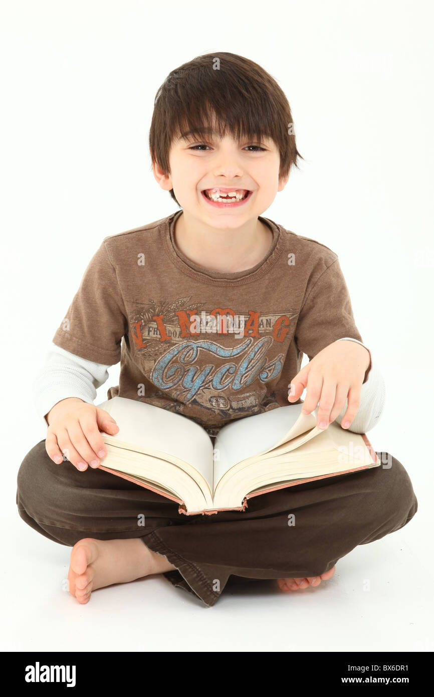Adorable seven year old french american boy with book over white background. Stock Photo