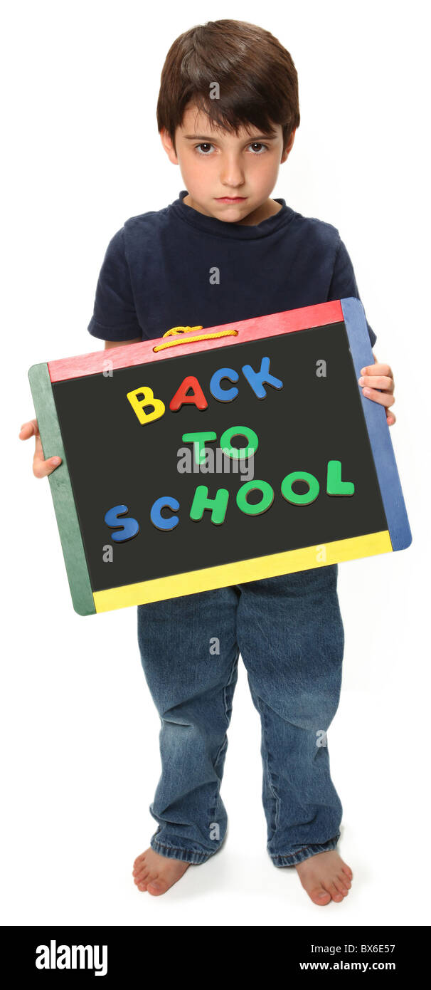 adorable unhappy seven year old boy holding blank chalk board that reads back to school Stock Photo