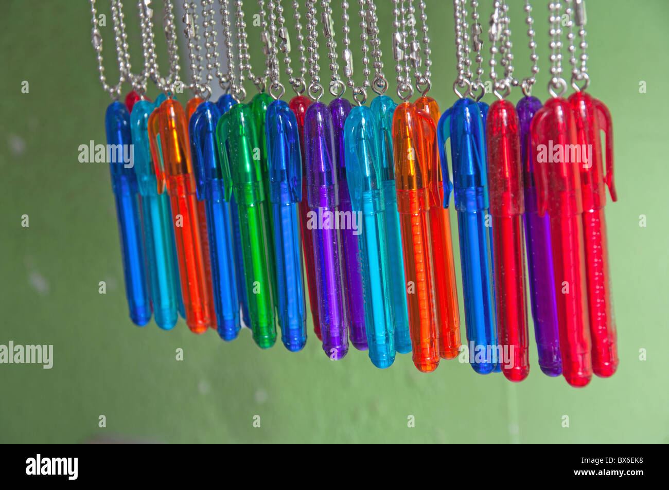 Diversicolorous ball pens on chains on a green background Stock Photo