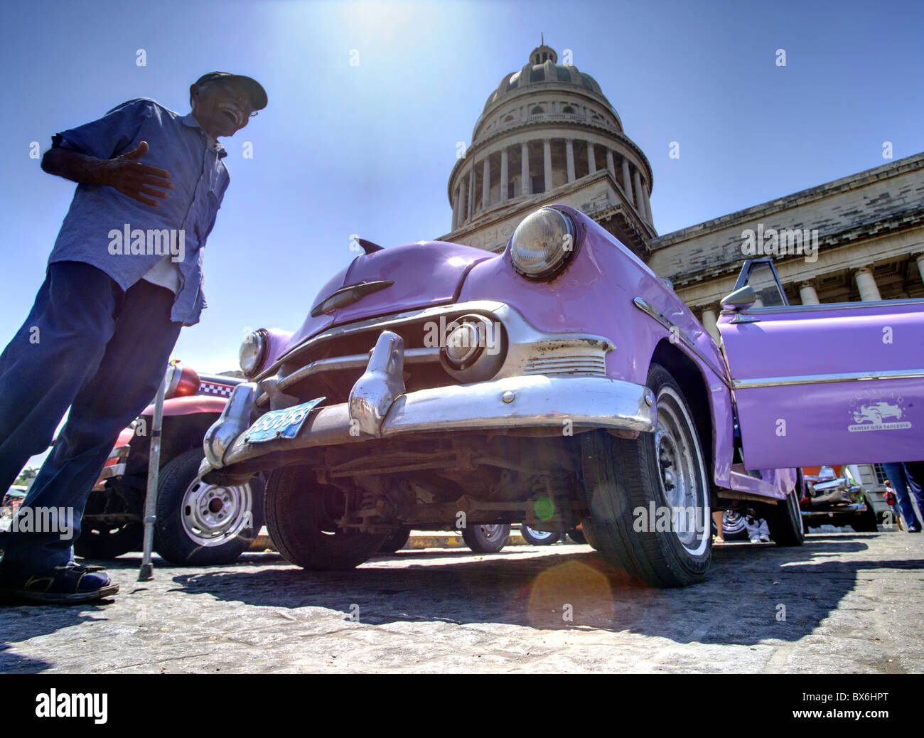 Low angle shot of The Capitolio with classic American car and old man in foreground, Havana, Cuba, West Indies Stock Photo