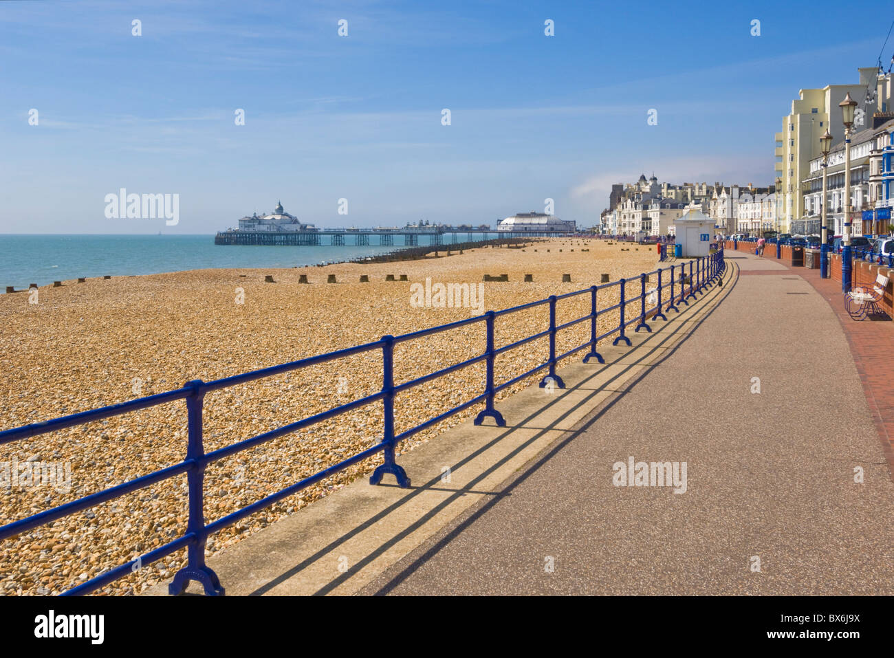 Pebble beach and groynes, hotels on the seafront promenade, Eastbourne pier in the distance, Eastbourne, East Sussex, UK Stock Photo
