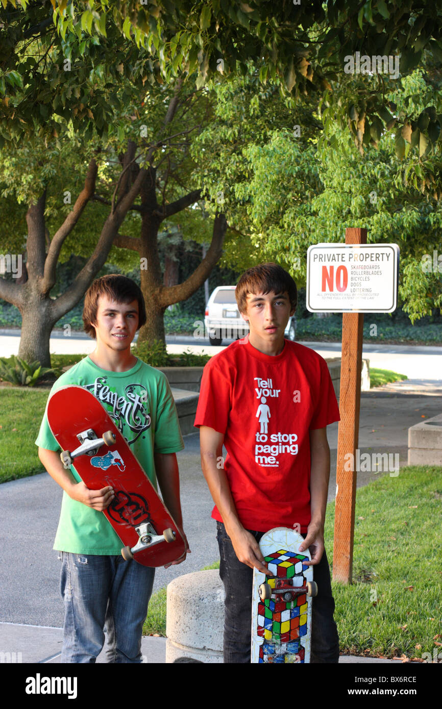 Teenage skateboarders hold their skateboards in front of a No Skateboarding sign. Modesto, California, U.S.A. Stock Photo