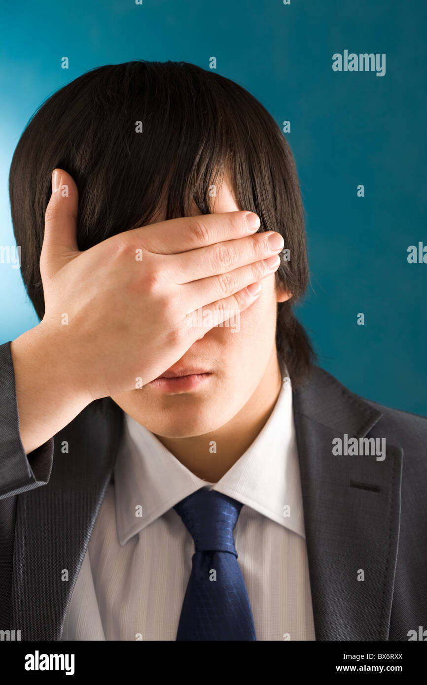 Portrait of young businessman hiding his face by hand Stock Photo