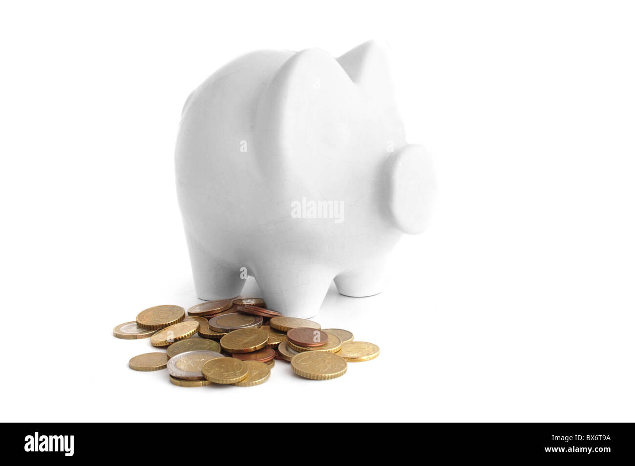 A piggy bank standing next to some money. All isolated on white background. Stock Photo