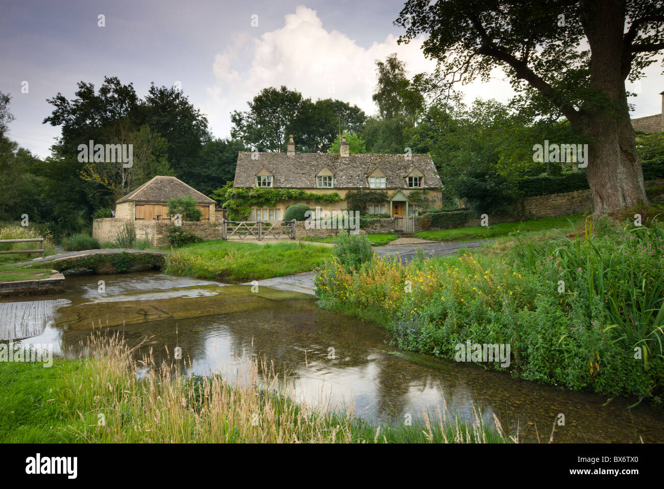 Cottage beside the River Eye in the picturesque Cotswold village of Upper Slaughter, Gloucestershire, England. Stock Photo