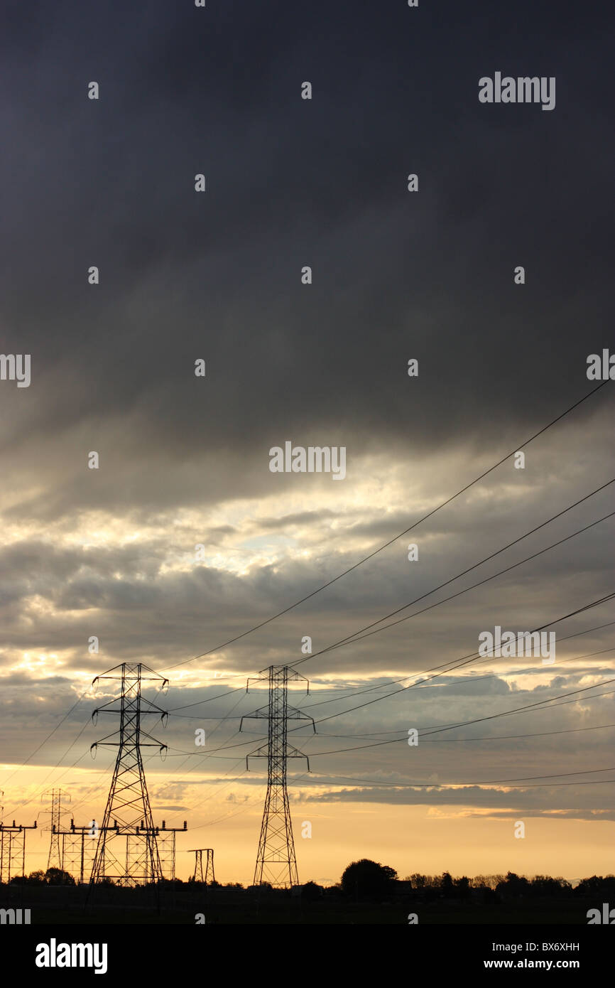 Transmission towers and power lines silhouetted against a dramatic ...