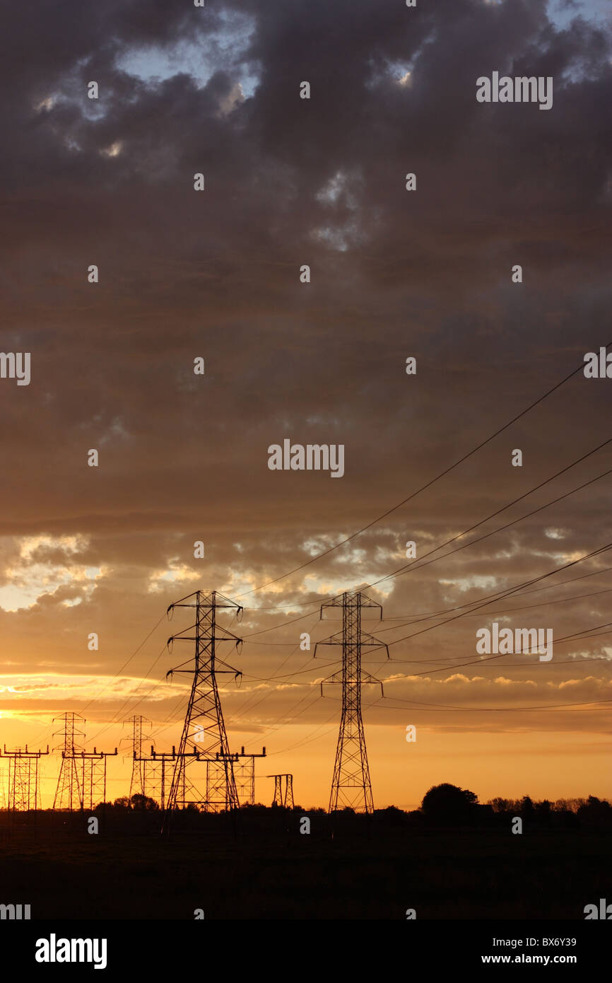 Transmission towers and power lines silhouetted against a dramatic ...
