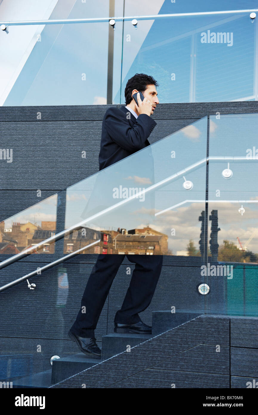 Business man walking up stairs while talking on the phone Stock Photo