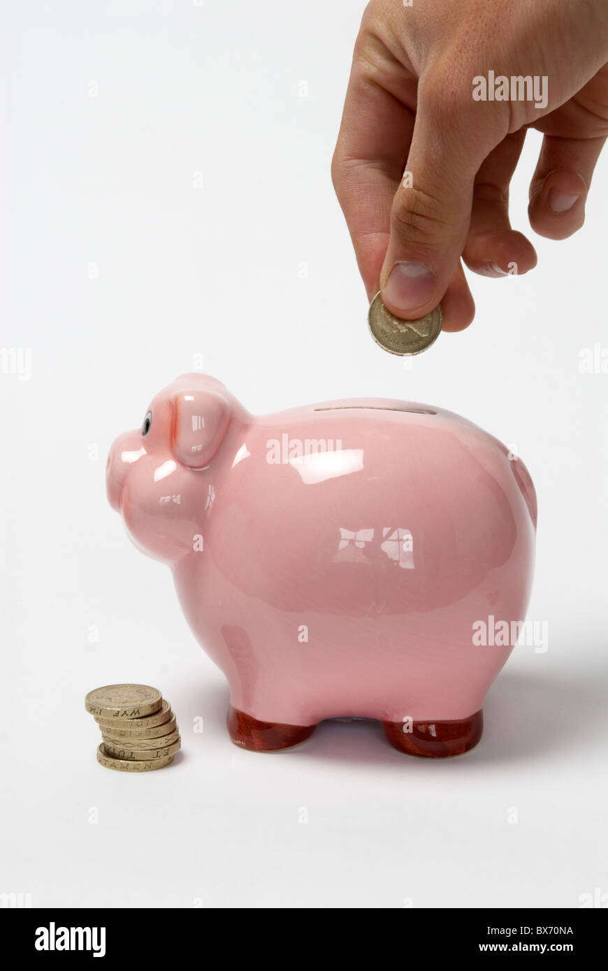 Hand putting coin into piggy Bank Stock Photo - Alamy