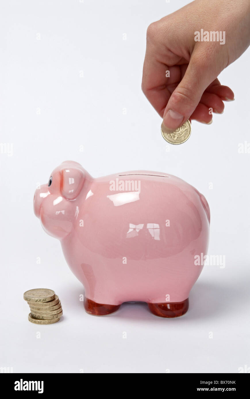 Hand putting coin into piggy Bank Stock Photo - Alamy