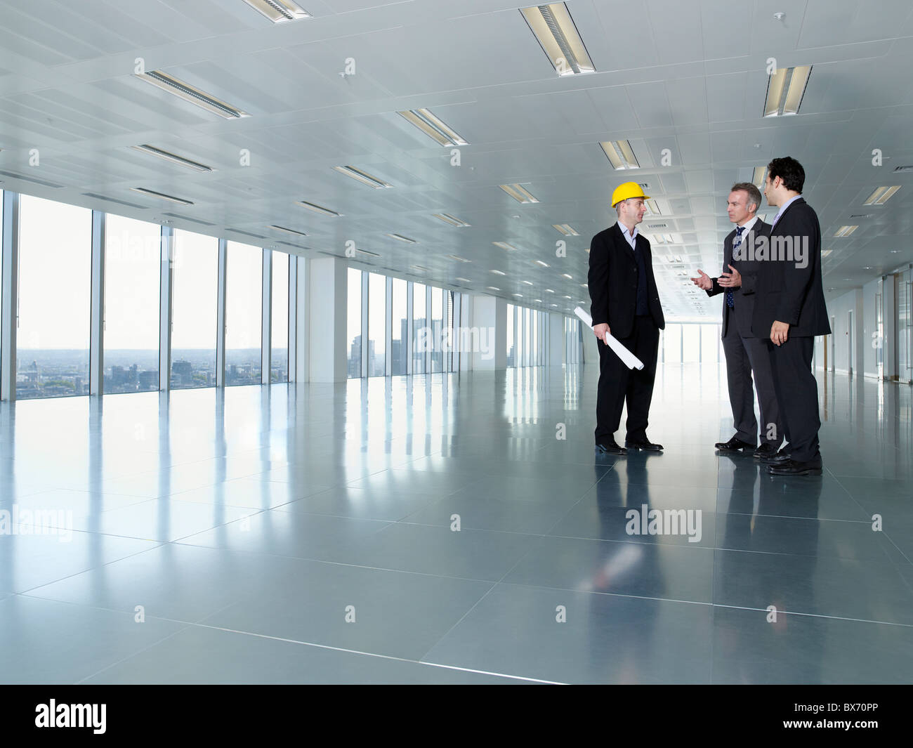 Three executives, one in hardhat, in empty office space Stock Photo