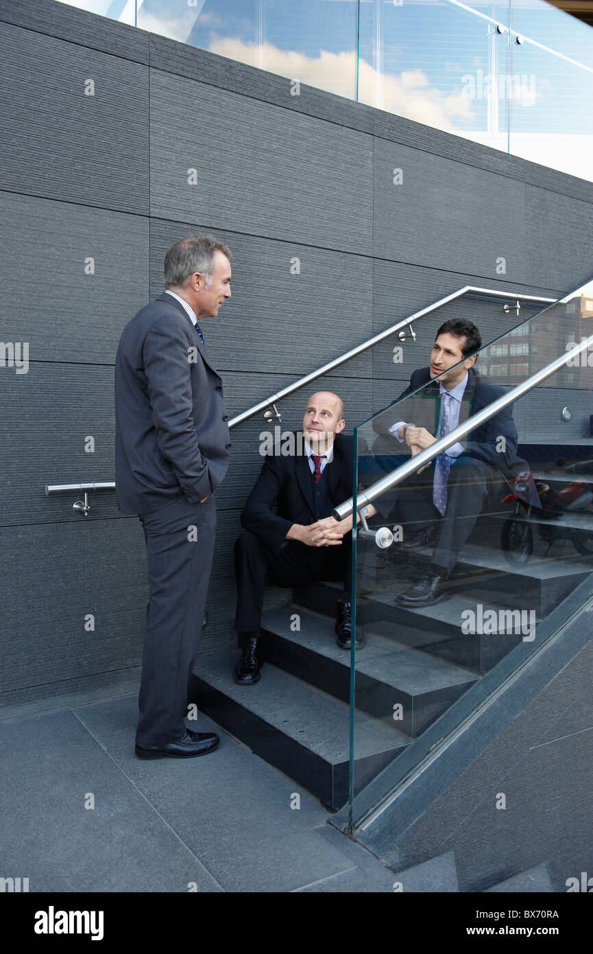 Business colleagues sitting on stairs having a chat Stock Photo