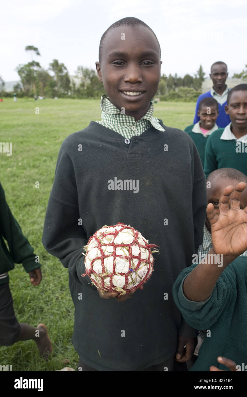 Schoolboy in school uniform holding football made from plastic bags and