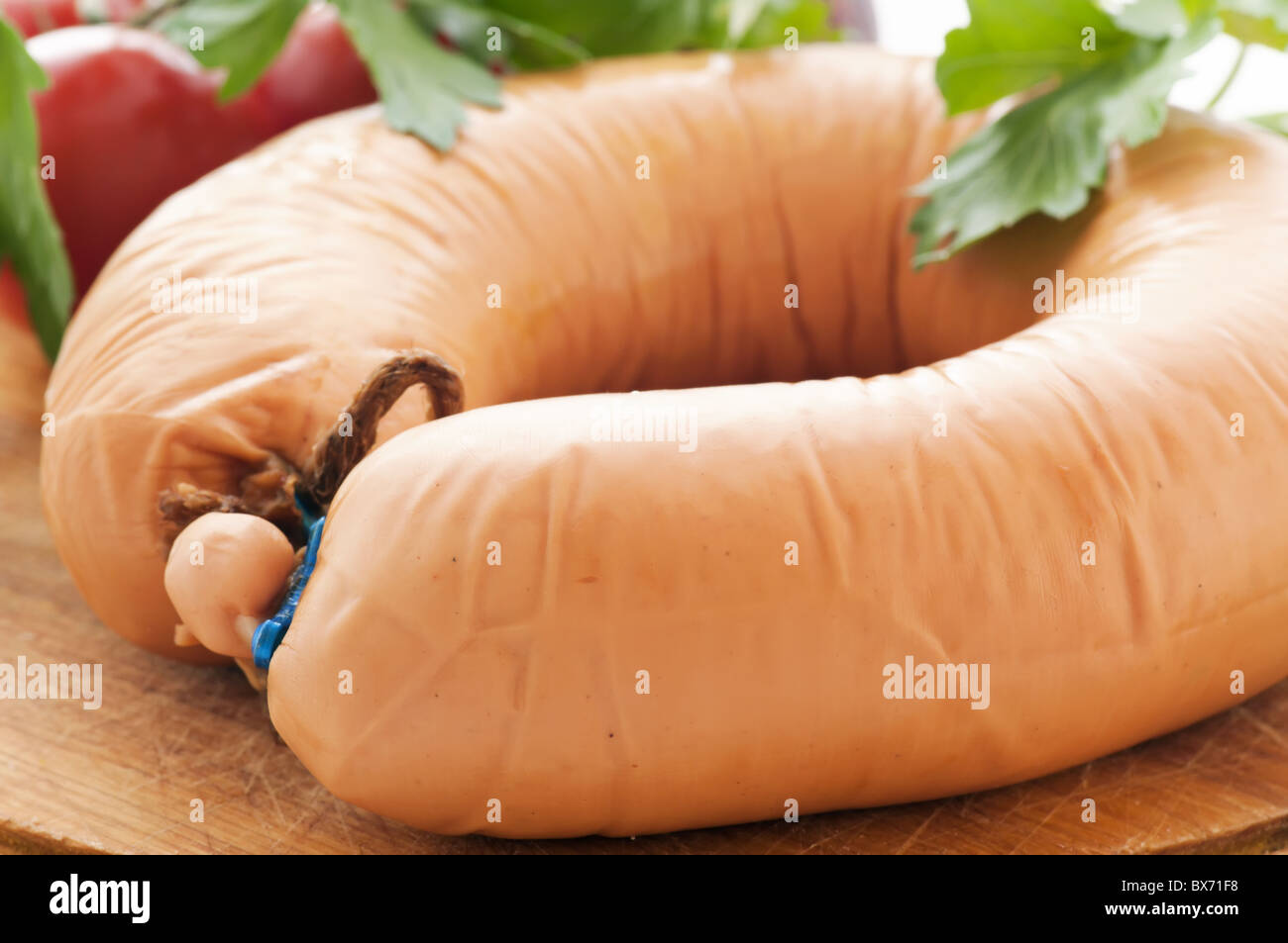 Traditional sausage ring with tomato and onion as closeup on a cutting