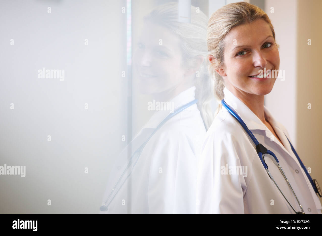 Doctor against a window, smiling Stock Photo